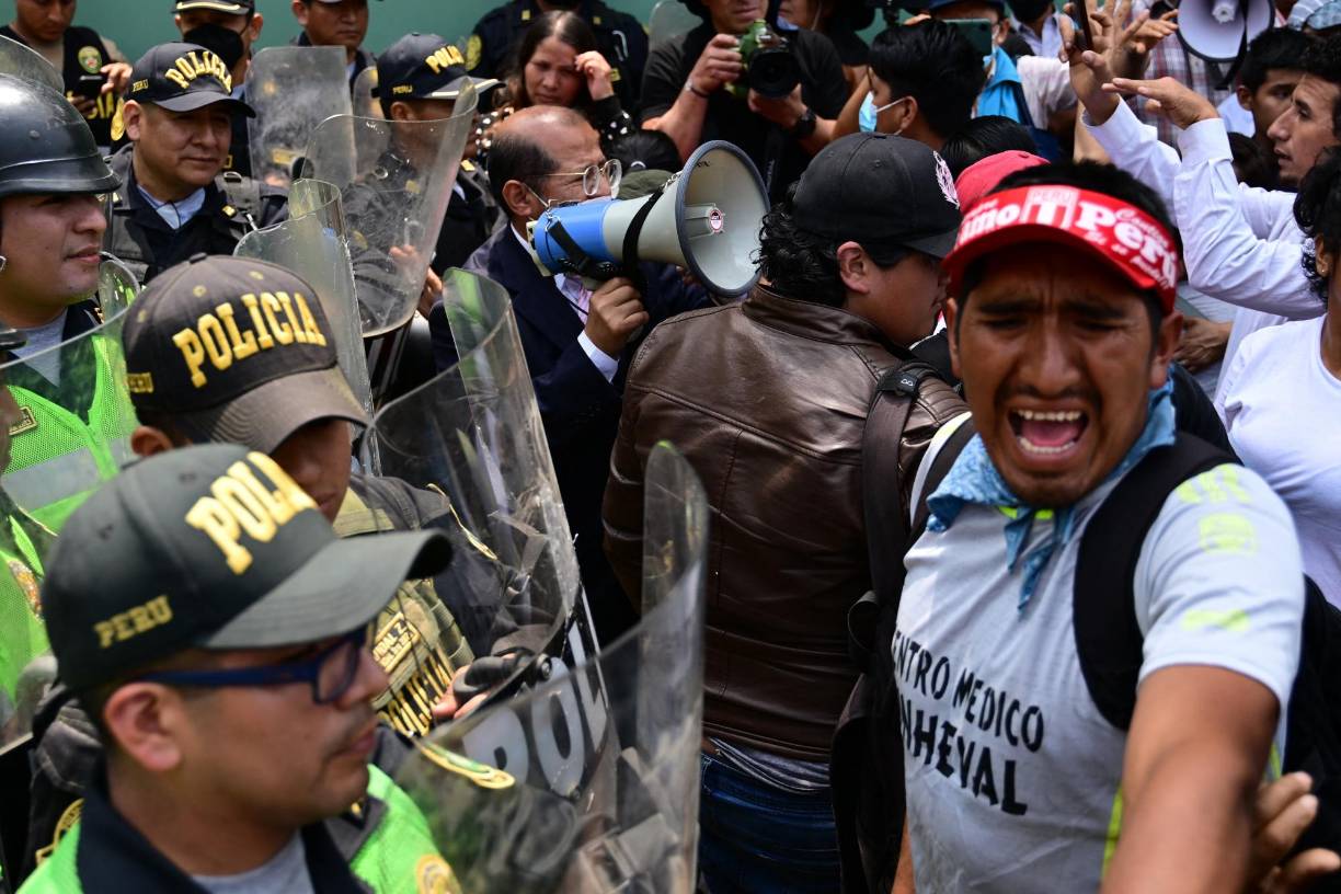 Supporters of Peruvian former President Pedro Castillo clash with the police during a demonstration demanding his release outside the police dependence DIROES in Ate, east of Lima, where Castillo is being held, on December 14, 2022. - Former Peruvian President Pedro Castillo, accused of "rebellion" and "conspiracy", will continue to be detained at a police base after an appeals court declared his request for freedom unfounded on Tuesday while protests that have left seven dead and 200 injured continue. (Photo by MARTIN BERNETTI / AFP)