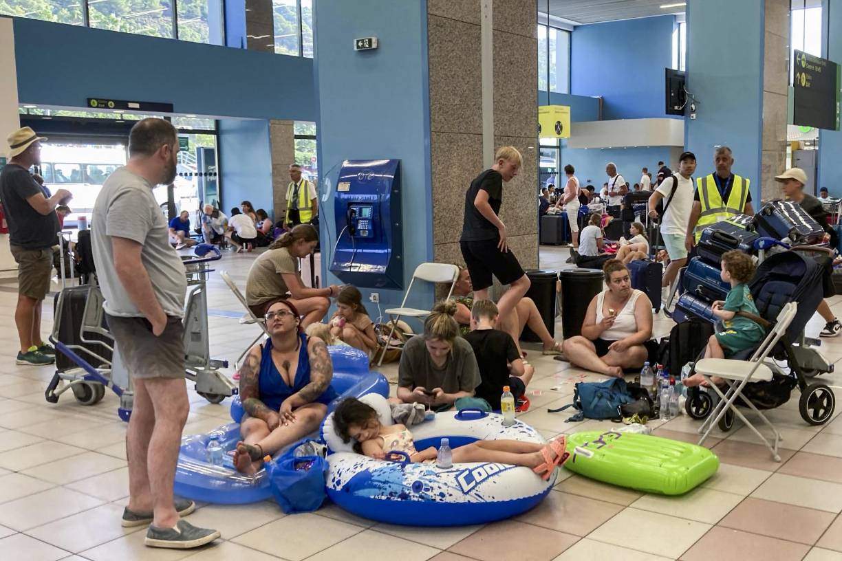 El aeropuerto de <b>Rodas</b> parecía este lunes un campamento improvisado a causa del incendio que arrasa parte de la isla griega, con temporeros descansando sobre toallas de playa y las sillas ocupadas por turistas todavía en bañador