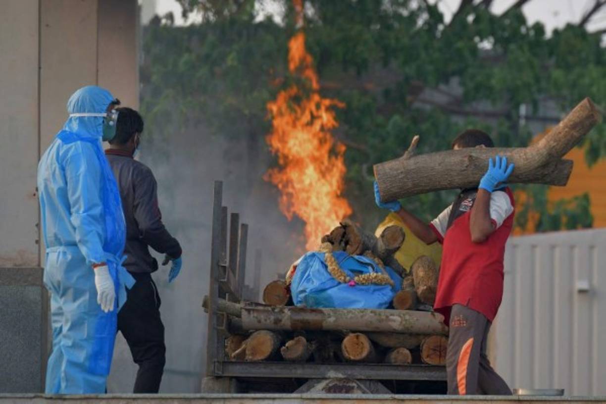 Family members and relatives perform final rites of a victim who died of the Covid-19 coronavirus at an open crematorium in Bangalore on April 26, 2021. (Photo by Manjunath Kiran / AFP)