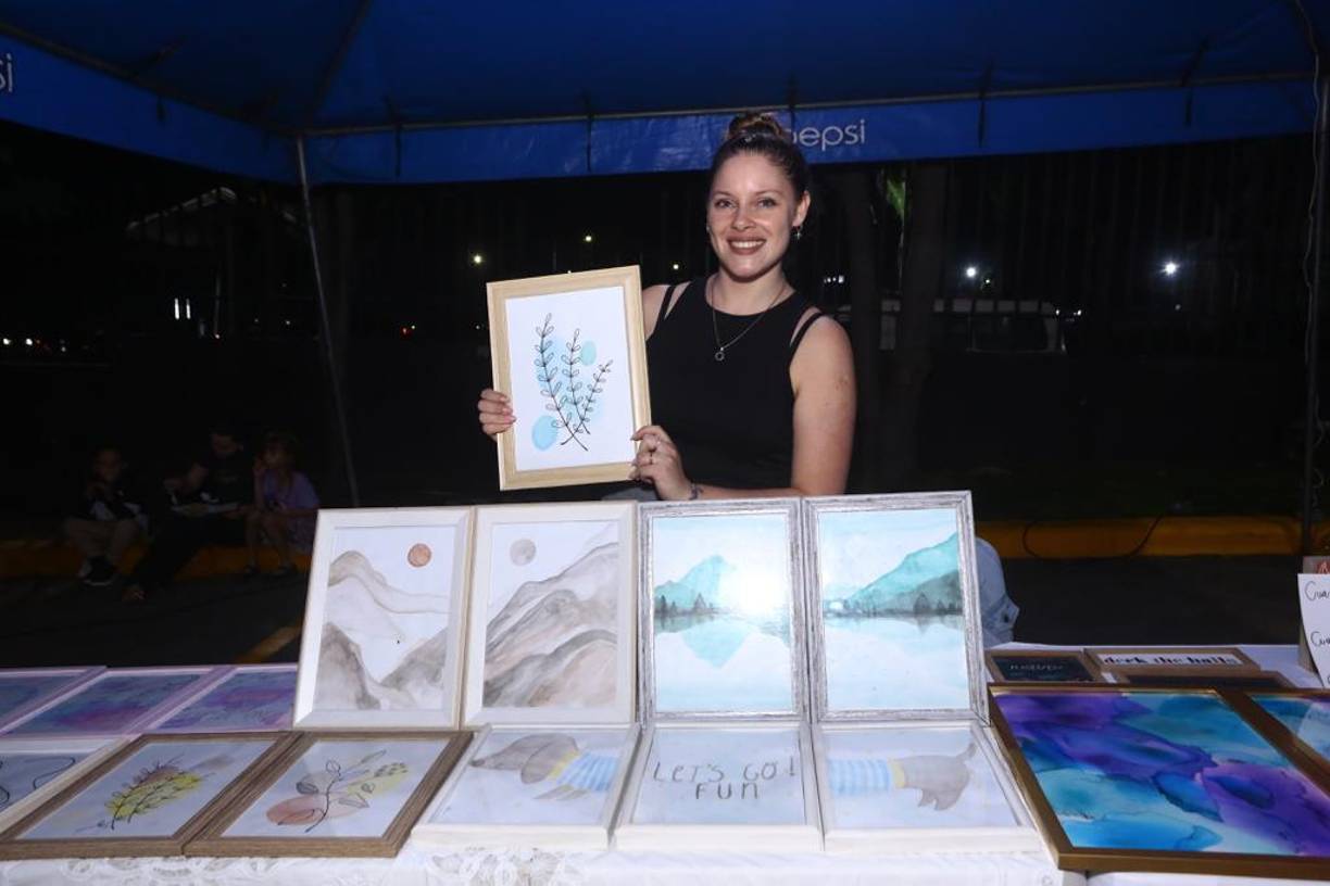 La artista Melisa RyL de Argentina mostrando sus cuadros hechos a mano.