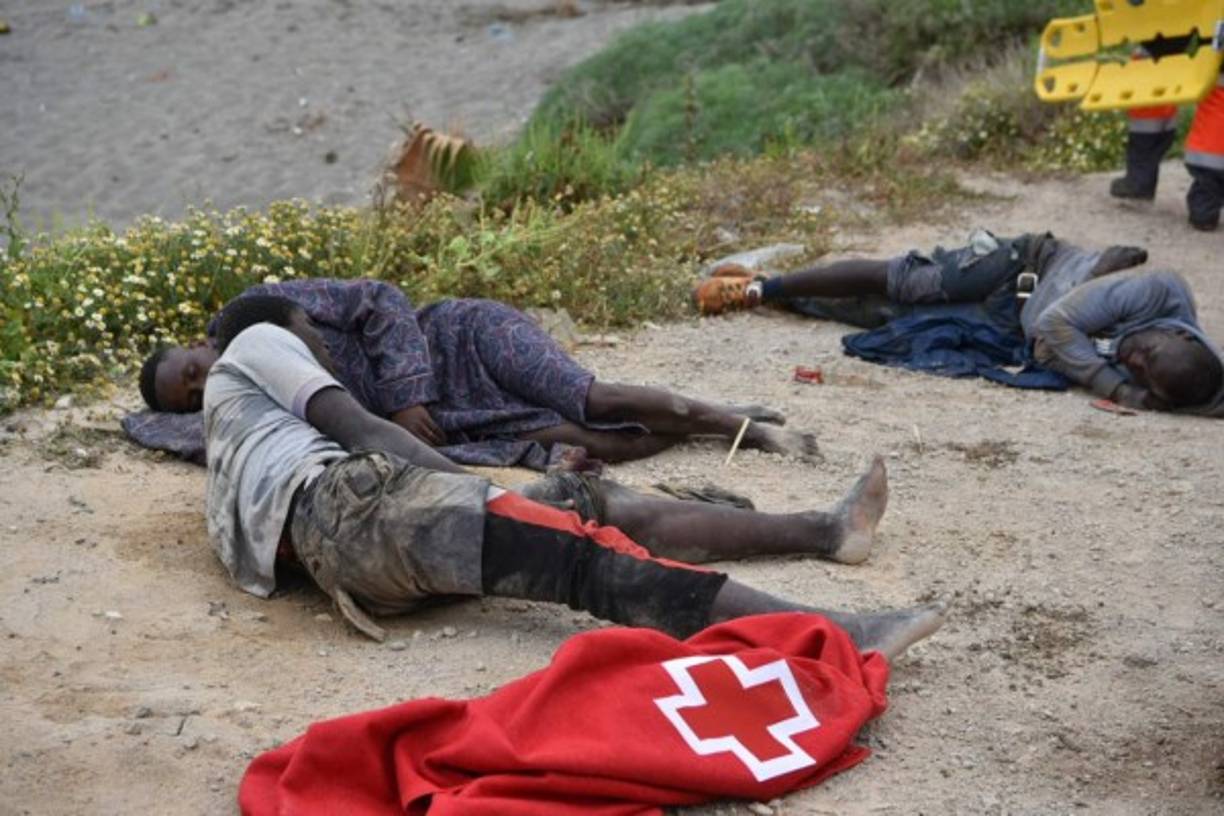 TOPSHOT - Migrants rest after swimming towards the shore of the Spanish enclave of Ceuta on May 18, 2021. - Spain has returned to Morocco nearly half of the 6,000 migrants who entered its Ceuta enclave, as hundreds more tried to enter its other north African territory. (Photo by Antonio Sempere / AFP)
