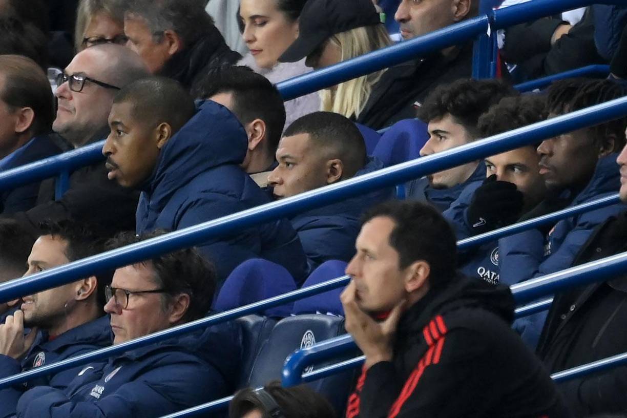 Kylian Mbappé observando el partido junto a los suplentes en el banquillo.