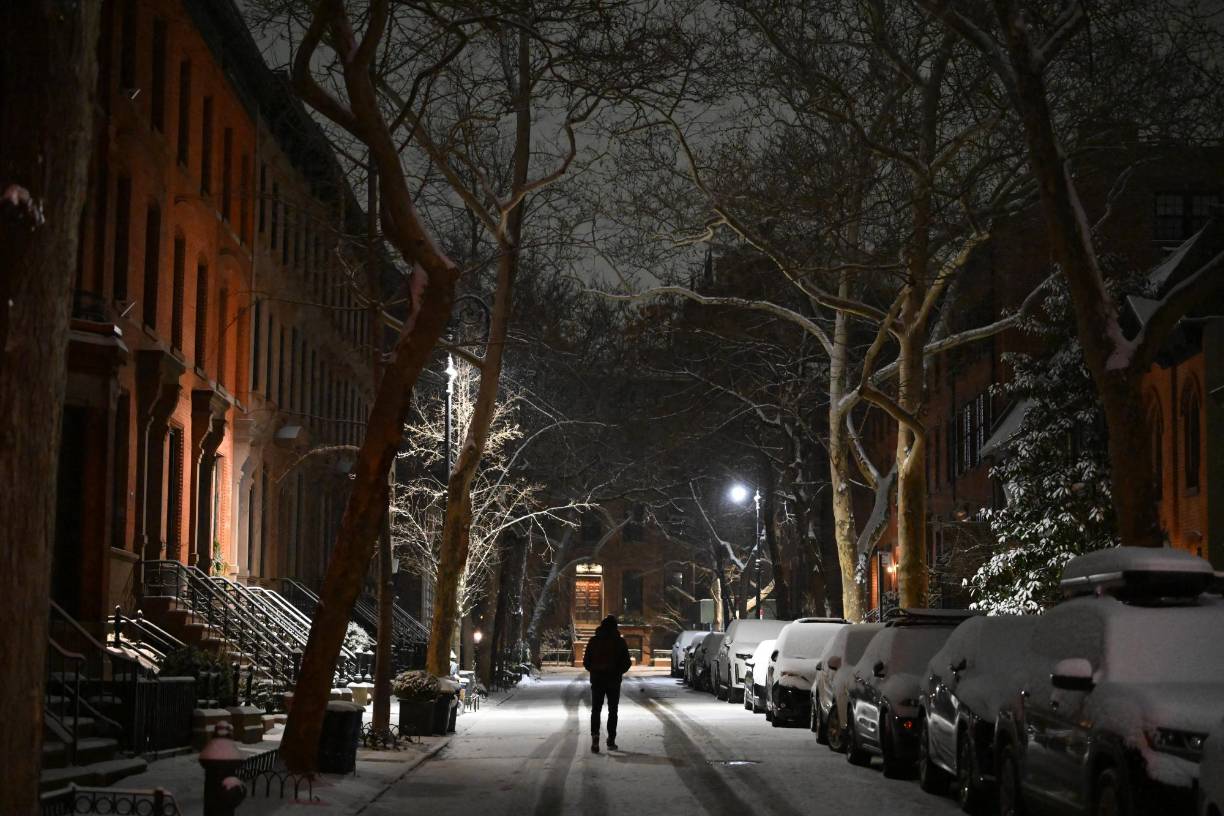 People walk through the snow in the Brooklyn Borough in New York on January 16, 2024. (Photo by ANGELA WEISS / AFP)