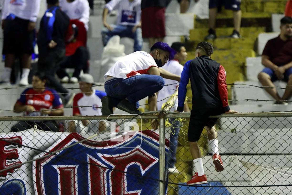 El riesgo que corren los aficionados del Olimpia al colocar las mantas en el cerco.