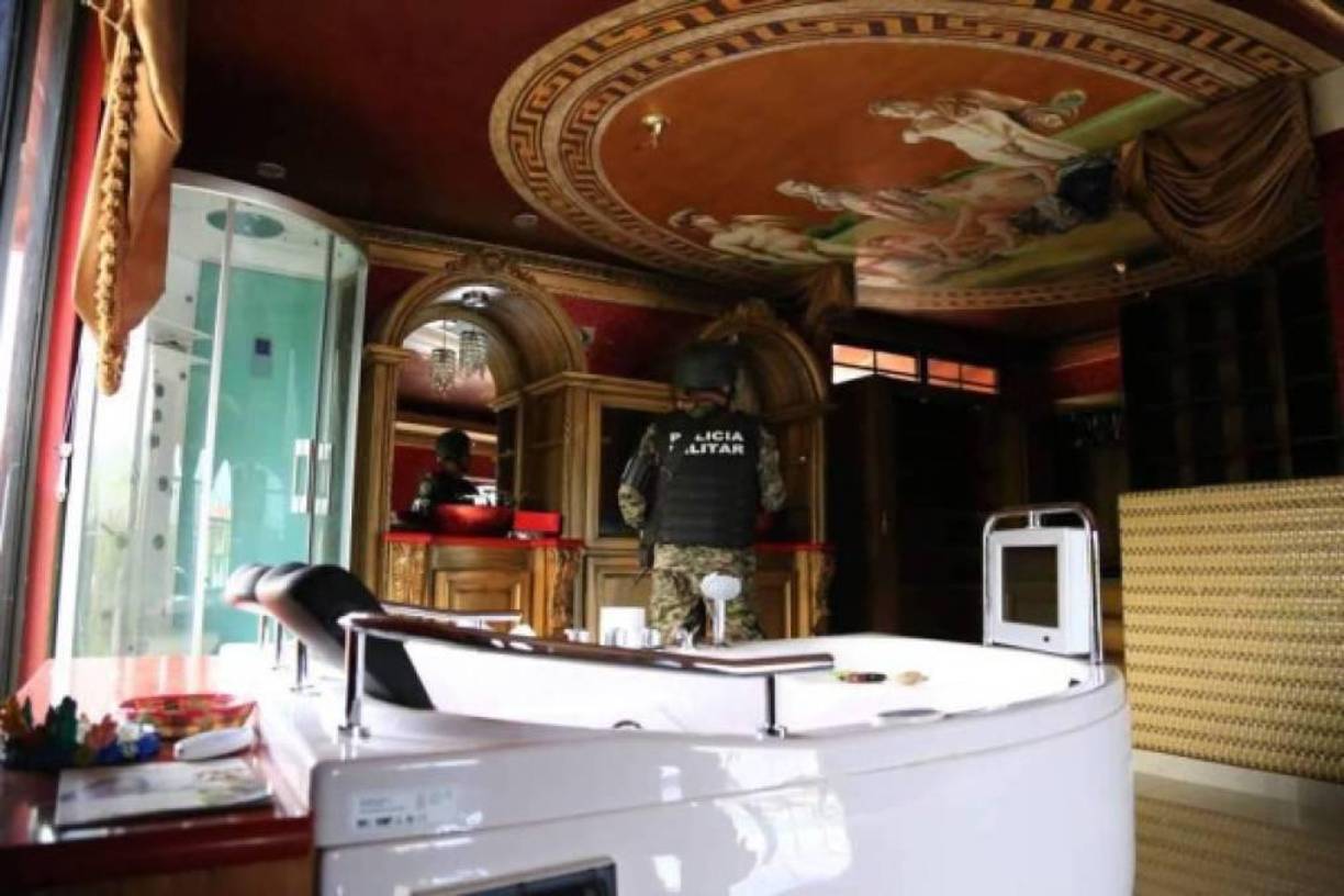 En esta habitación se aprecia un lujoso jacuzzi, una baño con puerta corrediza transparente y una especie de pintura en el techo.