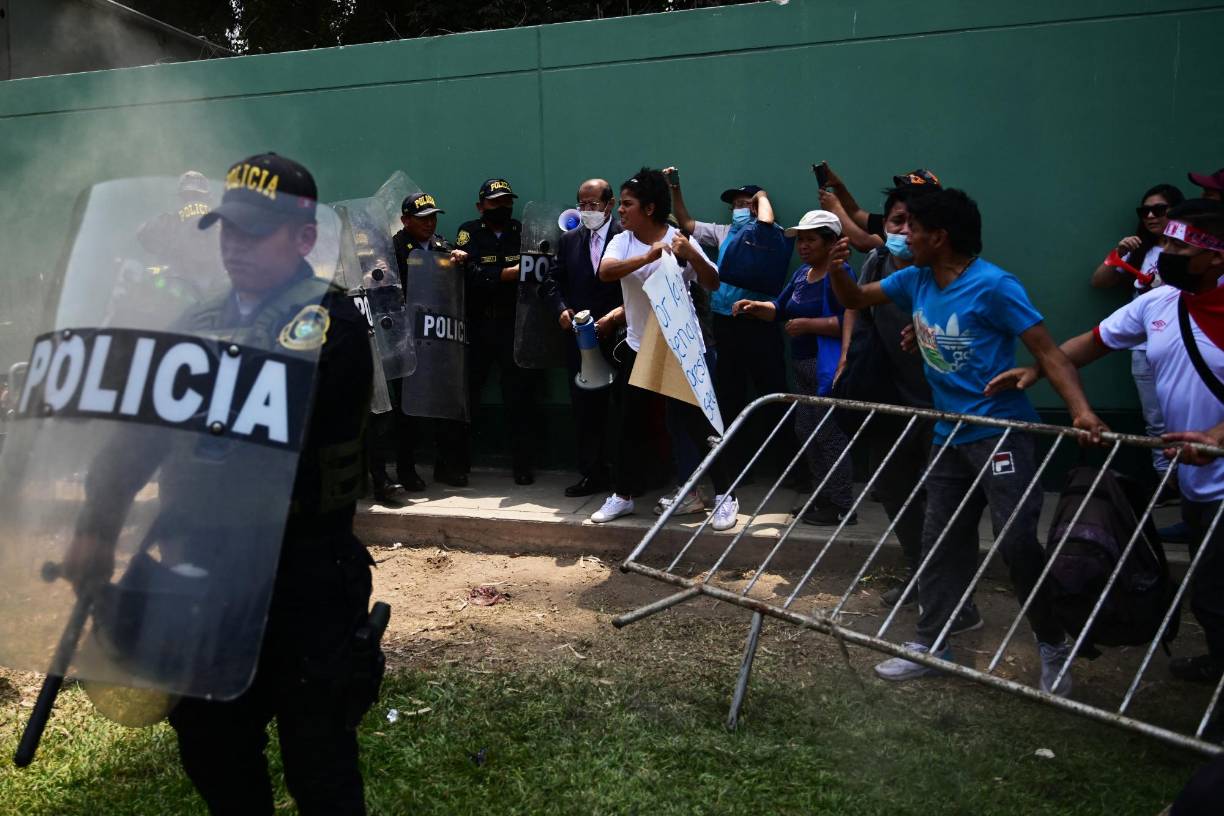 Supporters of Peruvian former President Pedro Castillo clash with the police during a demonstration demanding his release outside the police dependence DIROES in Ate, east of Lima, where Castillo is being held, on December 14, 2022. - Former Peruvian President Pedro Castillo, accused of "rebellion" and "conspiracy", will continue to be detained at a police base after an appeals court declared his request for freedom unfounded on Tuesday while protests that have left seven dead and 200 injured continue. (Photo by MARTIN BERNETTI / AFP)