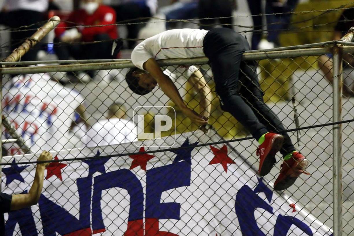 El riesgo que corren los aficionados del Olimpia al colocar las mantas en el cerco.