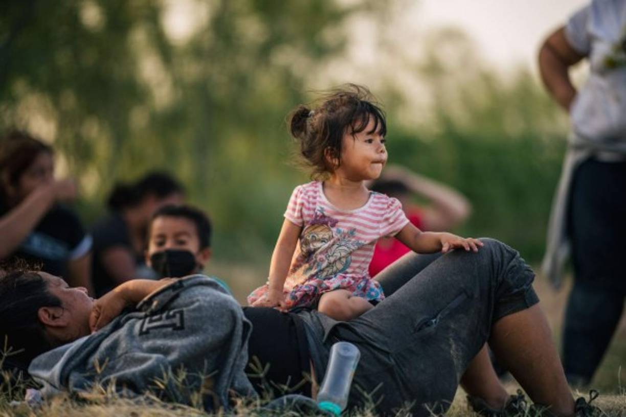 LA JOYA, TEXAS - JUNE 21: Migrant families wait to be accounted for and taken to a border patrol processing facility after crossing the Rio Grande into the U.S. on June 21, 2021 in La Joya, Texas. A surge of mostly Central American immigrants crossing into the United States has challenged U.S. immigration agencies along the U.S. Southern border. Brandon Bell/Getty Images/AFP<br/><br/>== FOR NEWSPAPERS, INTERNET, TELCOS & TELEVISION USE ONLY ==<br/><br/>
