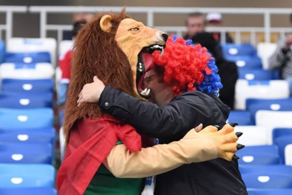 Un hombre vestido de león hace como que se va a comer a un aficionado.