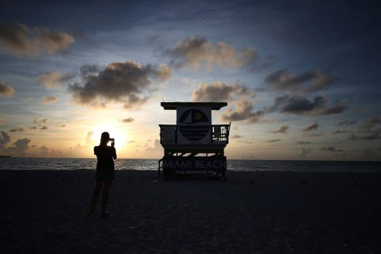Unos pocos turistas se atreven a dar un paseo por las playas de Miami Beach.