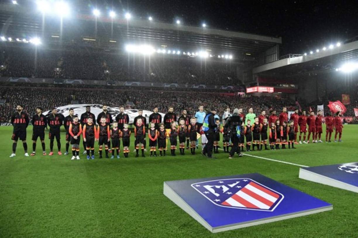 Los jugadores de Atlético y Liverpool en el campo de Anfield mientras suena el himno de la Champions League.