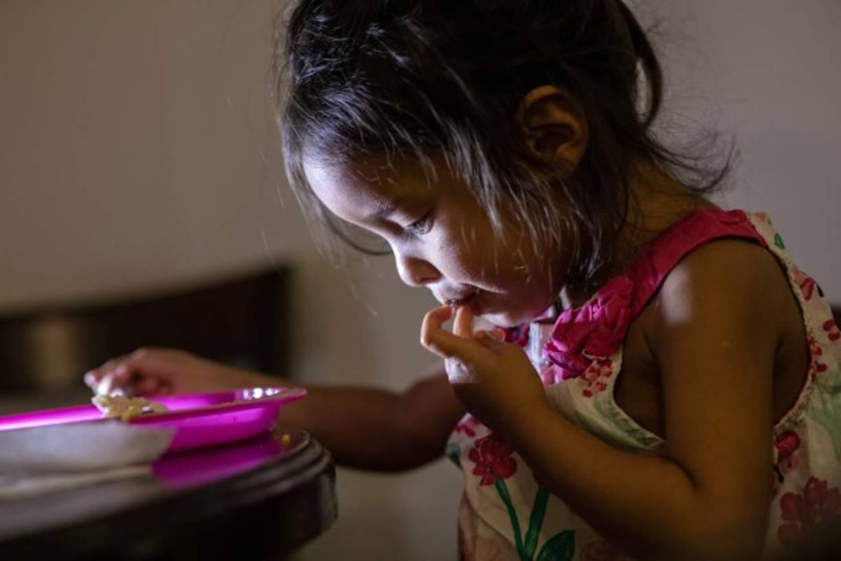 La niña hondureña Yanela Sánchez come en el apartamento que ella y su madre Sandra Sánchez comparten con otros inmigrantes el 11. AFP