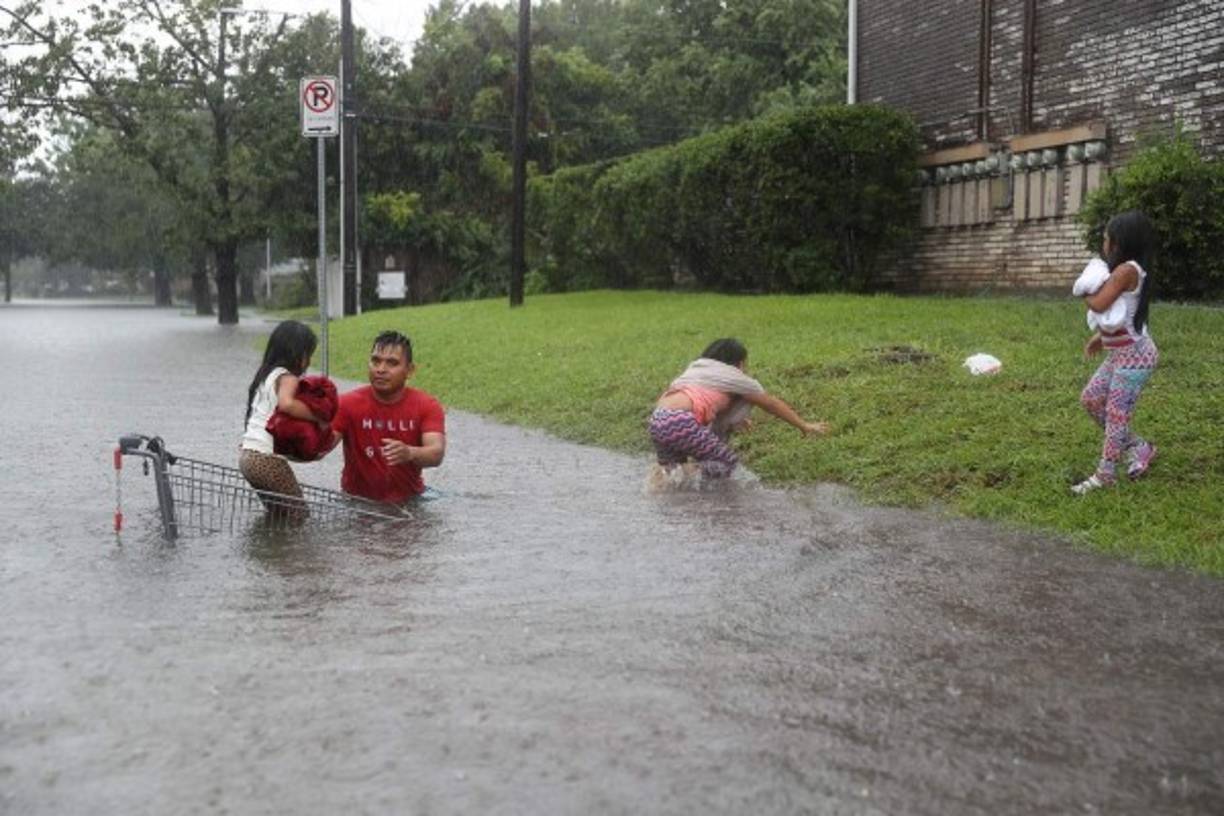 Un padre hispano intenta huir de las inundaciones con sus hijas.