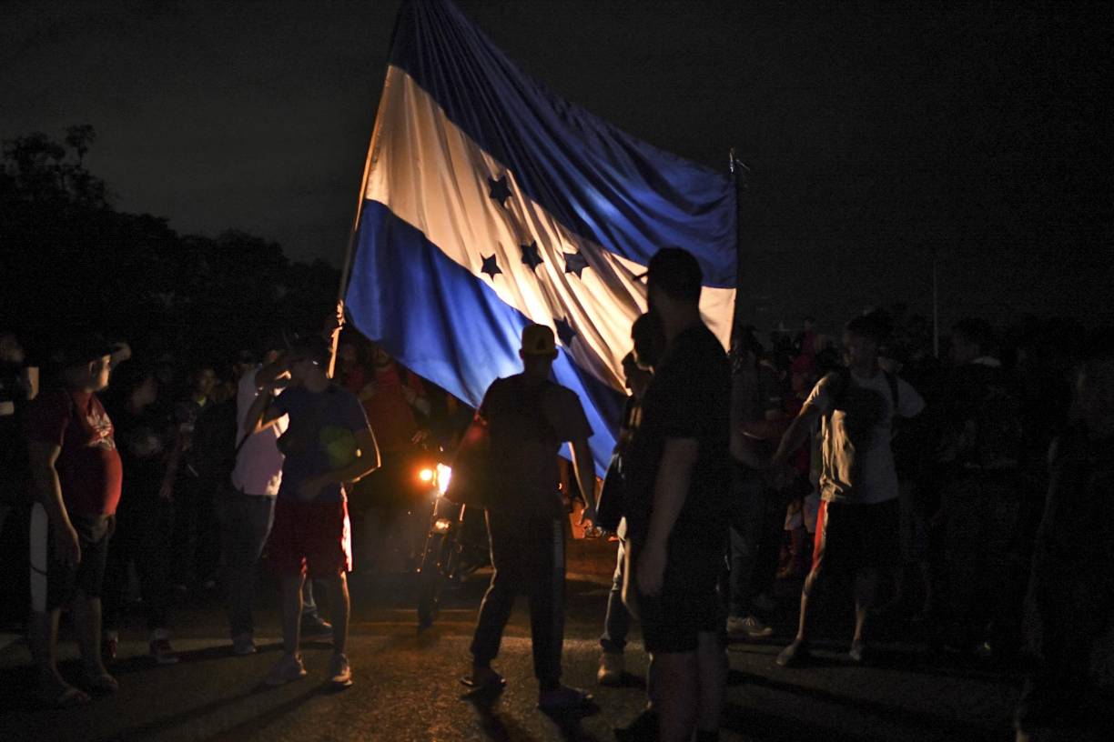Los migrantes llevan una gigantesca bandera de Honduras que sobresale en el recorrido.