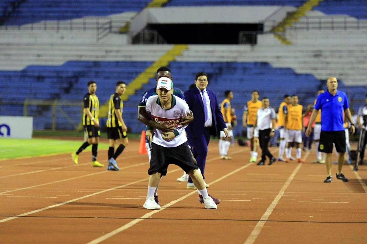 Clayvin Zúniga se arriesgó tratando de controlar a este aficionado que buscaba lanzar piedras a los aficionados del Real España.