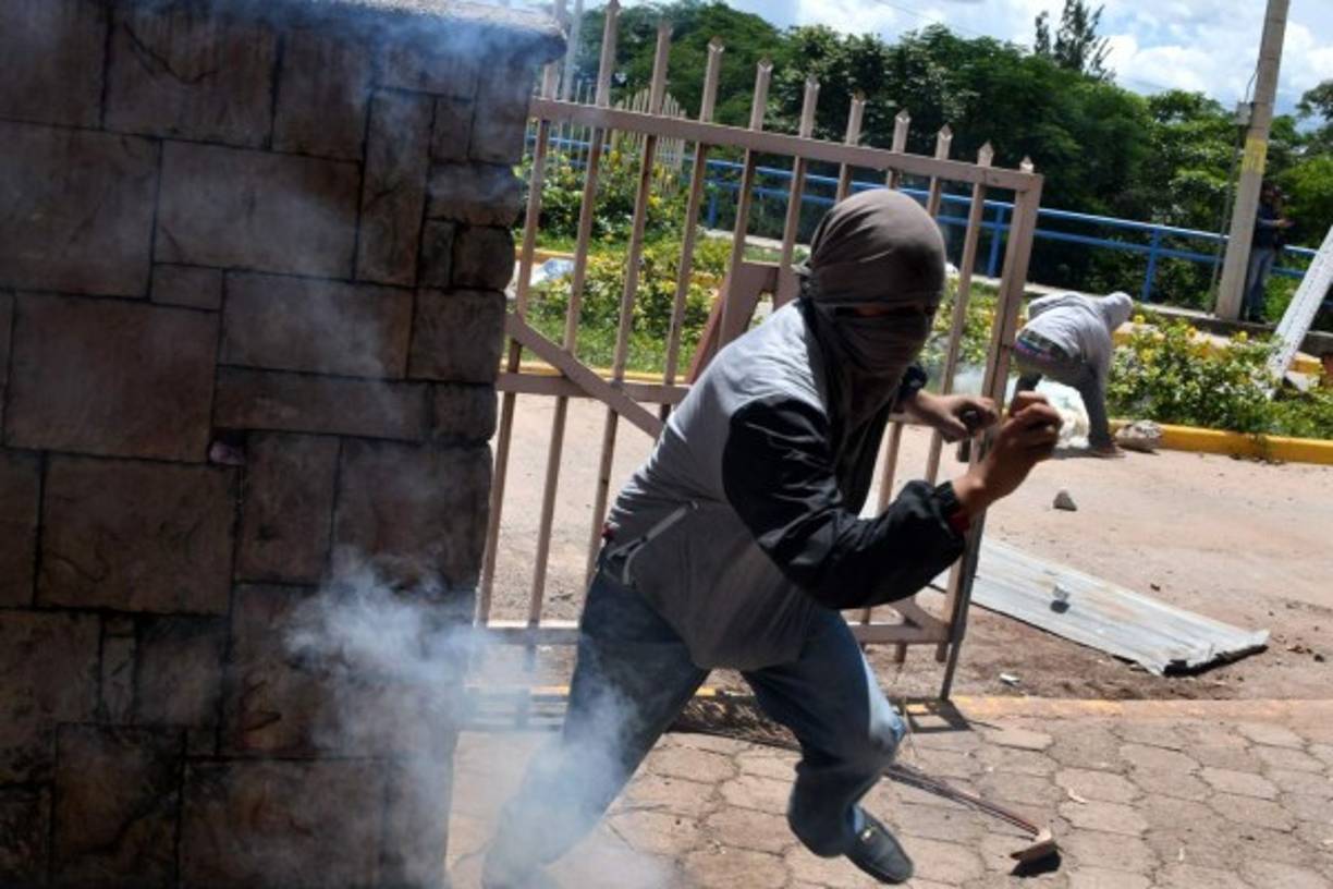 Los estudiantes encapuchados del Movimiento Estudiantil Universitario (MEU) se enfrentaron con la policía en el bulevar Suyapa de Tegucigalpa. AFP