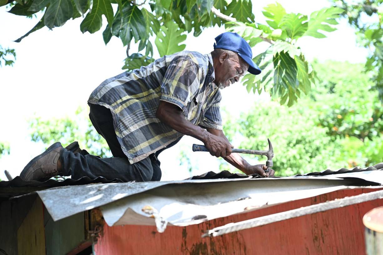 Un hombre protege el techo de su casa con laminas de zinc ante la inminente llegada del huracán Beryl en Saint Thomas (Jamaica). 