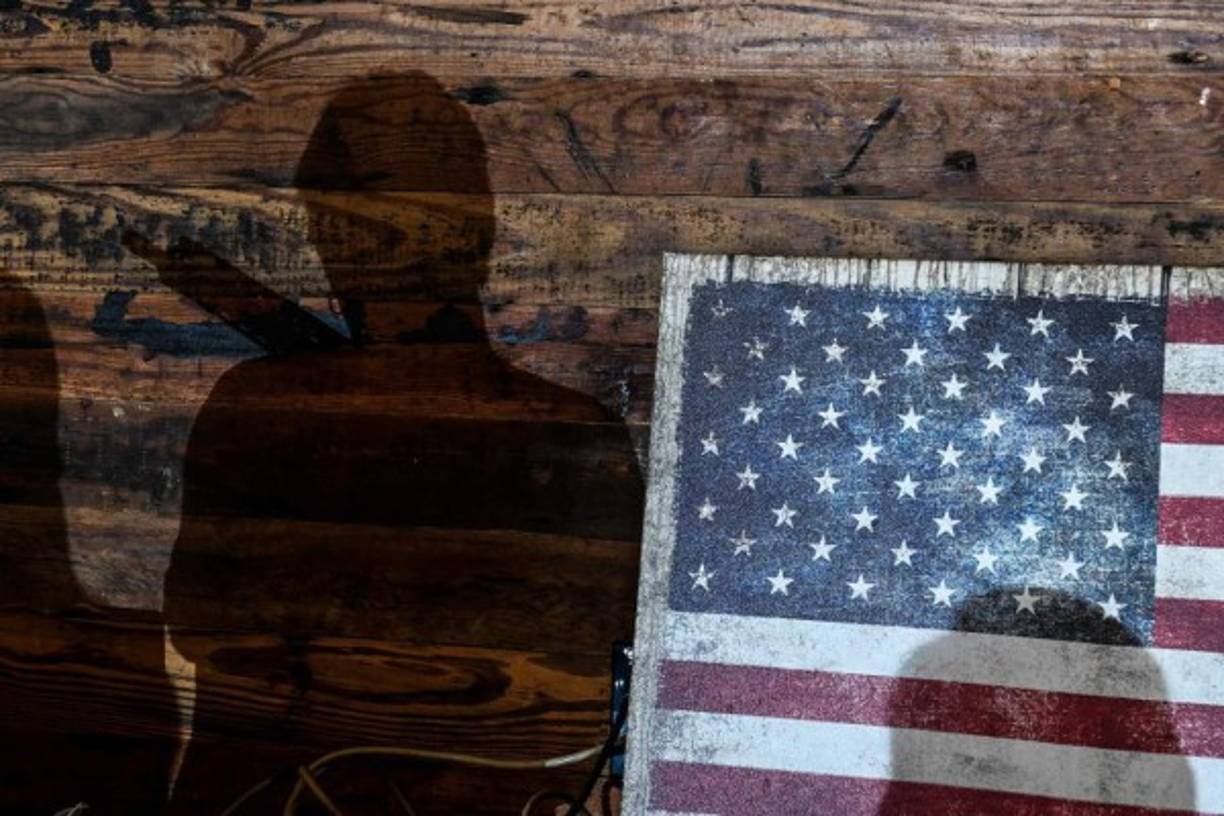 The shadow of a student is seen next to a US flag during an AR-15 semi-automatic rifle shooting course at Boondocks Firearms Academy in Jackson, Mississippi on September 26, 2020. - From the countryside to the cities, Americans are engaged in a frenzy of gun-buying fueled by the pandemic, protests and politics. (Photo by CHANDAN KHANNA / AFP)