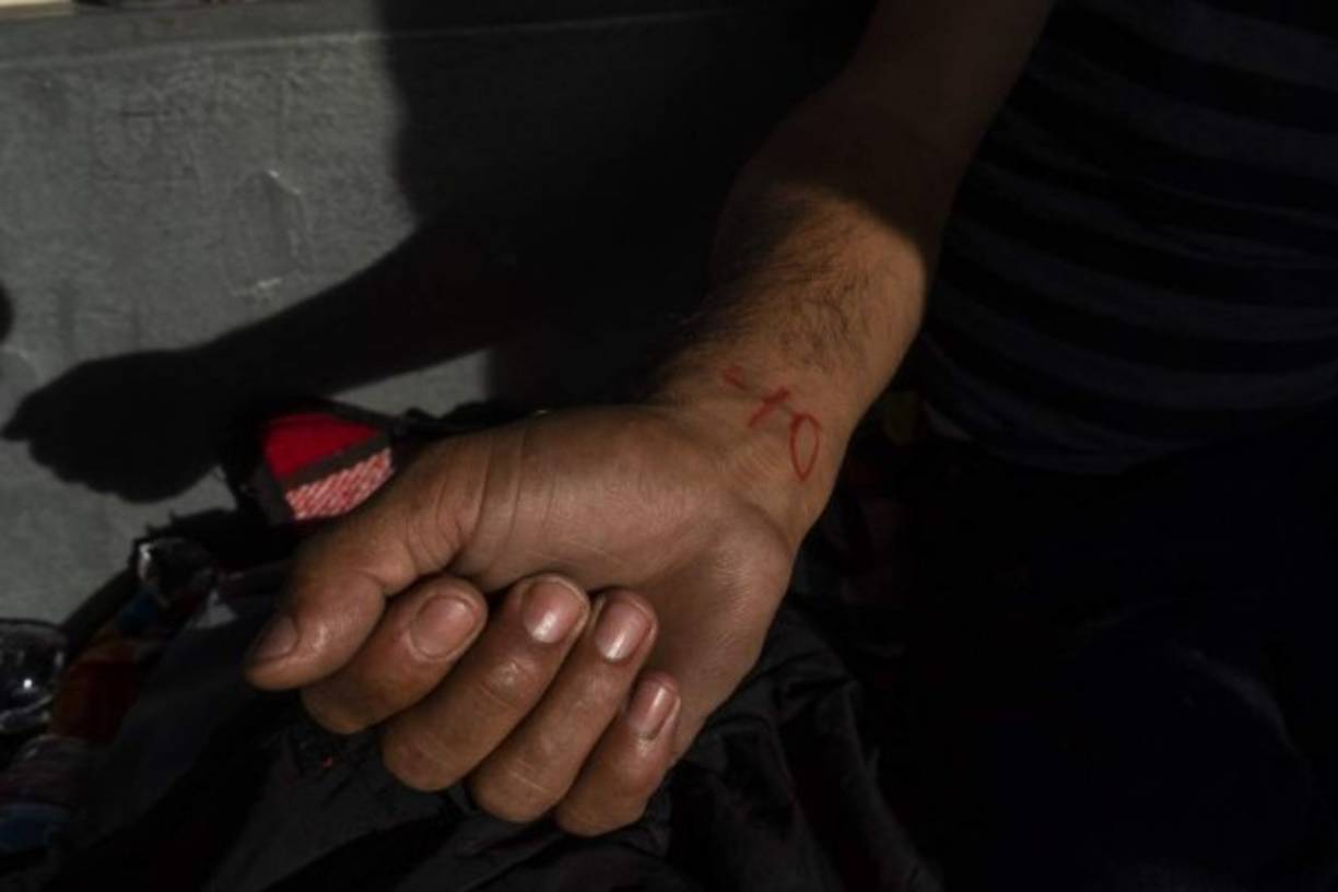 Los migrantes fueron marcados con su número en la fila para evitar conflictos en el paso fronterizo, indicaron autoridades locales.