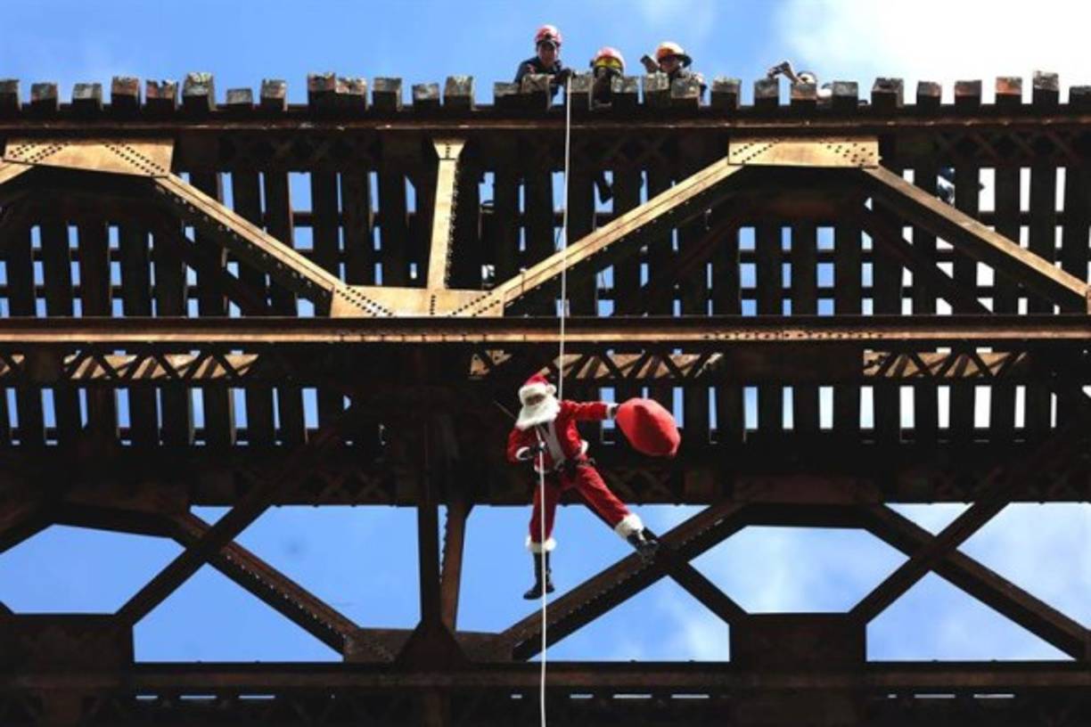 Un Santa Claus bombero desciende a rapel de uno de los puentes más altos de ciudad de Guatemala en el barrio Jesús de la Buena Esperanza, uno de los más pobres de la ciudad.