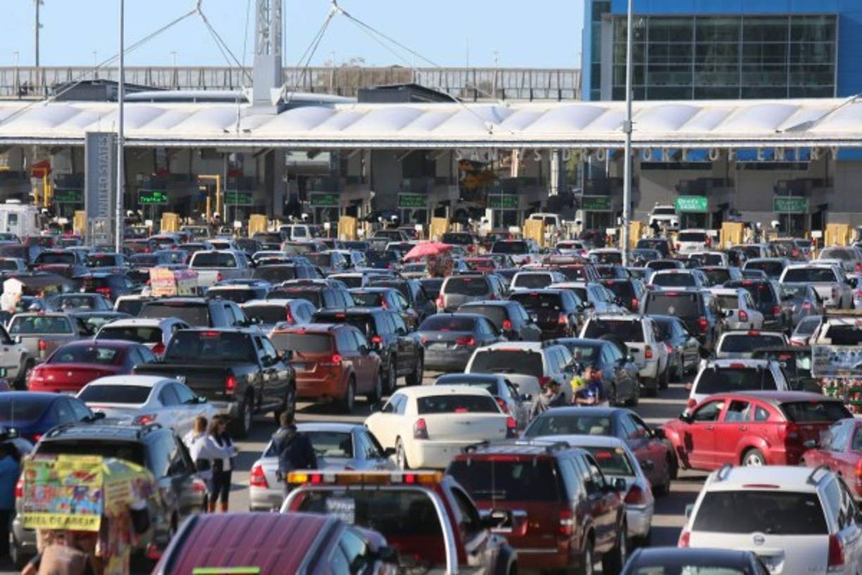 Centenares de personas cruzan de un país a otro por dos puentes peatonales, mientras una fila inmensa de automóviles se concentra en la zona de control fronterizo.