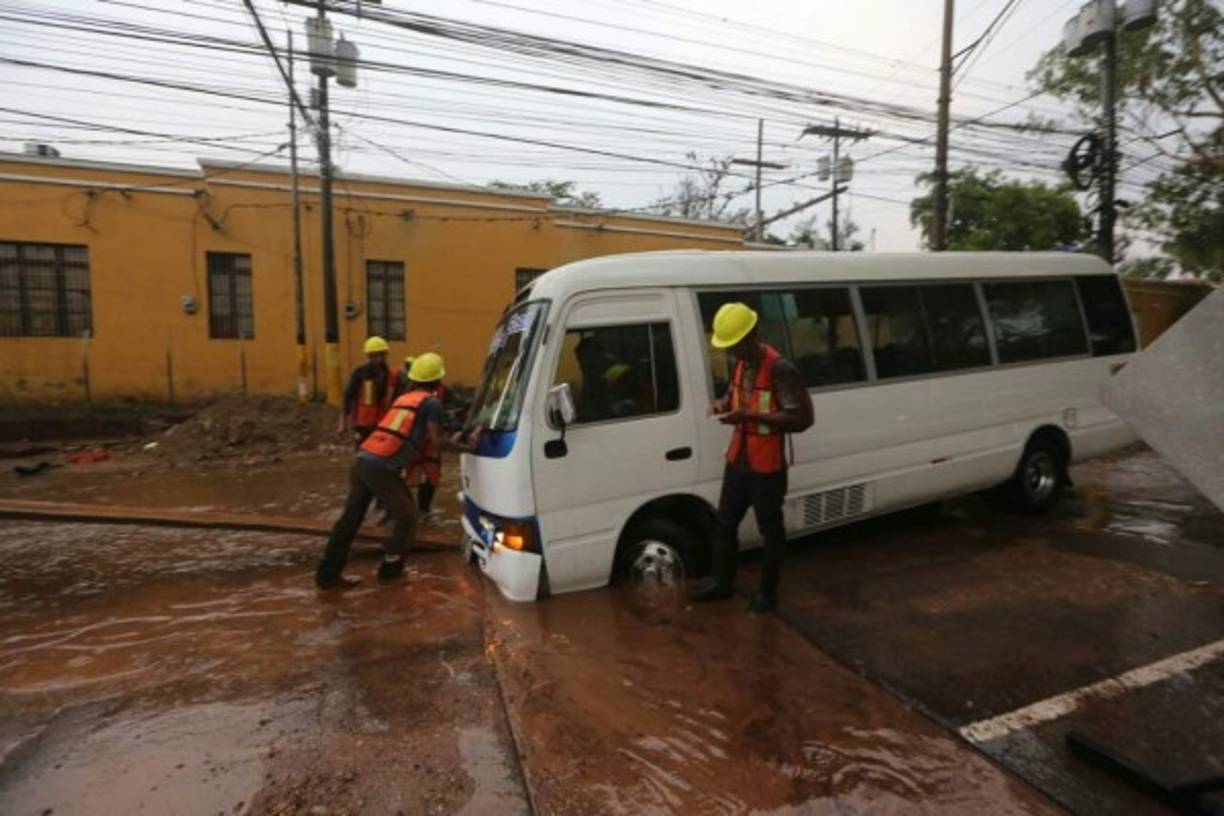 Diferentes unidades de transporte fueron abandonadas al momento de las lluvias. En la imagen, varios hombres intentan sacar un busito que se quedó atascado en una calle.