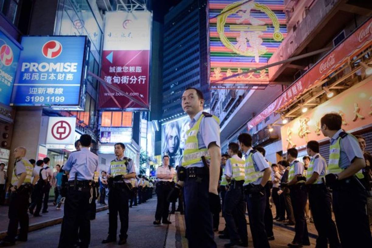 Policías a pie de una escena en la que los manifestantes se enfrentaron contra los manifestantes pro-democracia en una zona ocupada de Hong Kong el 3 de octubre de 2014. AFP