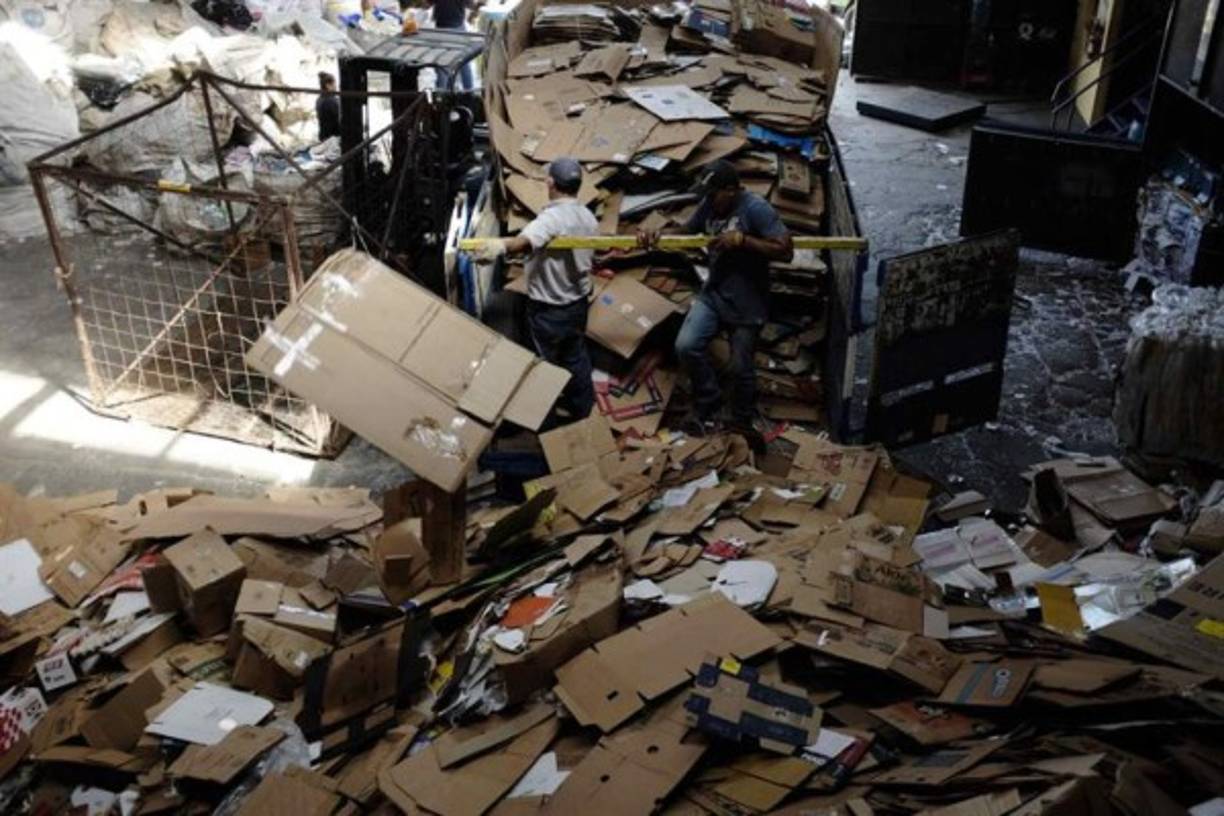 Dos hombres reciclando en San José (Costa Rica). Mucho del material recolectado por los 'cartoneros' es ordenado y separado para su reciclaje. Invisibles ante los ojos de los transeúntes citadinos, los 'cartoneros', en su mayoría indigentes, al ritmo de las hormigas de trabajo recolectan los cartones desperdigados de los comercios de la capital en San José, Costa Rica. La suma del material recopilado por los cartoneros puede ascender a 8 toneladas diarias, según comenta Víctor Calvo, propietario del centro de reciclaje donde se realiza el acopio de los desechos en San José. Con una paga por kilo de 35 colones ($0,06), se convierte en un pequeño ingreso para estas personas que en su mayoría son dependientes de las drogas y que por esta labor muchos han dejado de robar. EFE/Jeffrey Arguedas.<br/><br/>