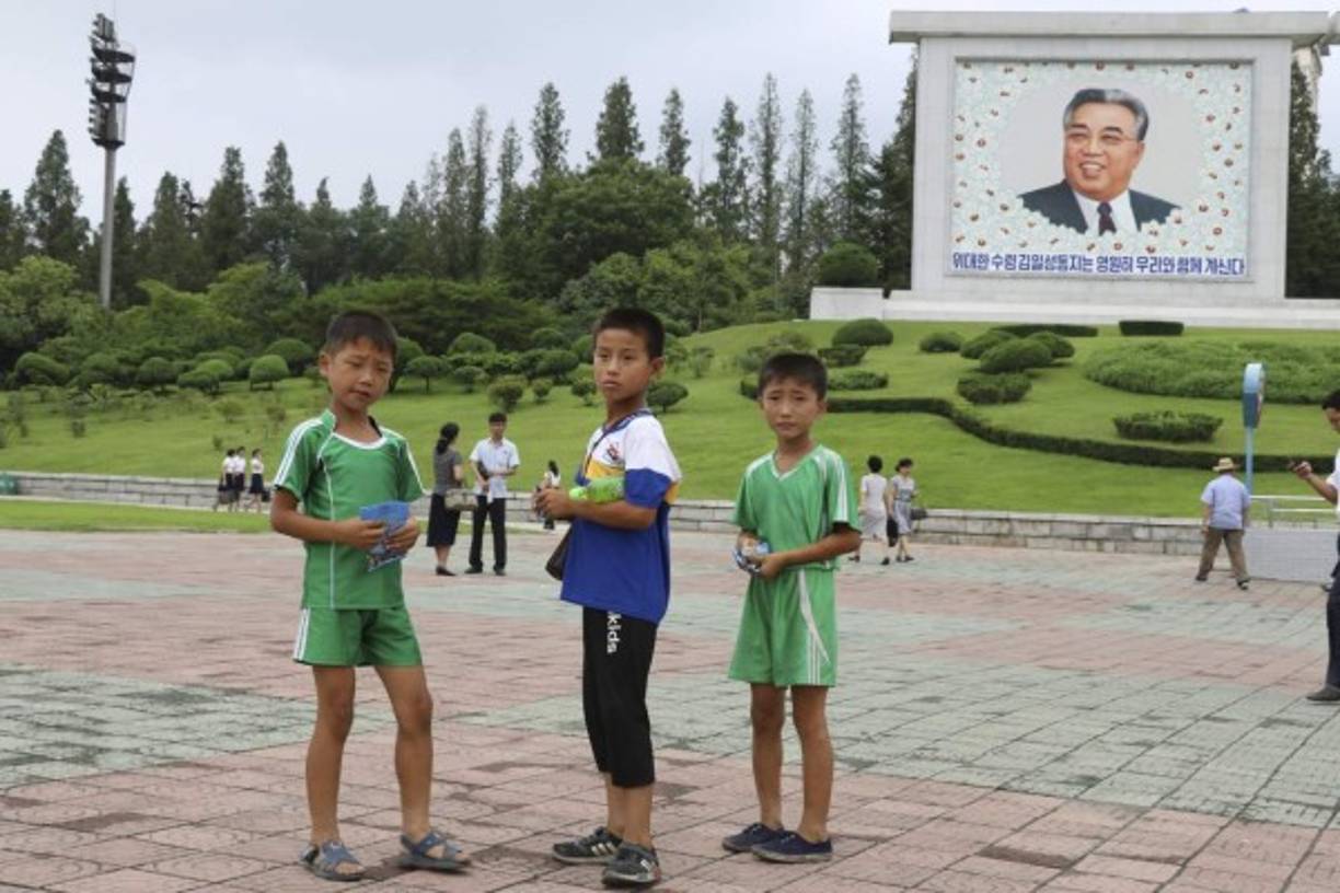 En un país, gobernado por la misma familia por tres generaciones, se rinde honor casi en cada esquina a los líderes pasados. En la imagen, tres niños juegan delante de un mosaico del líder y fundador del país Kim Il sung en la avenida Mansudae de Pyongyang.