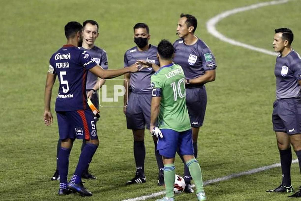 Los capitanes Marcelo Pereira, de Motagua, y Nicolás Lodeiro, del Seattle Sounders, se saludan junto a la cuarteta arbitral.