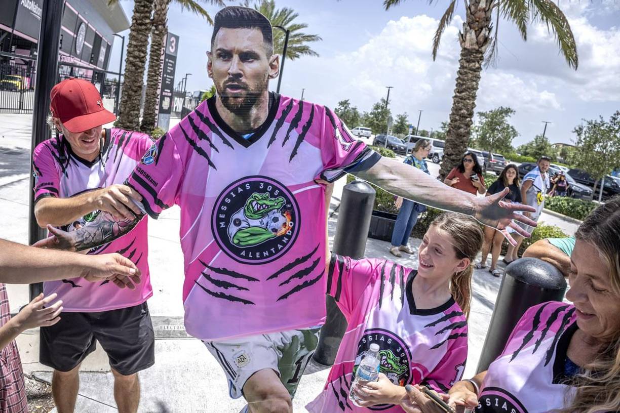 Aficionados del Inter Miami con una figura recortable de cartón de Lionel Messi en las afueras del estadio DRV PNK.