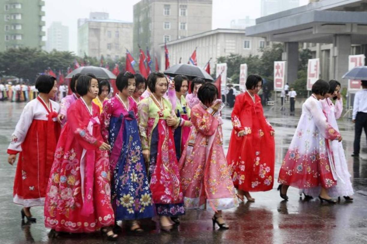 Varios periodistas han viajado recientemente a la capital norcoreana para retratar el día a día de los ciudadanos, en momentos de tensión ante Corea del Sur, Japón y EUA. Y se encontraron con imágenes como esta, un grupo de jóvenes con trajes tradicionales, mojándose bajo la lluvia tras participar en un evento callejero, sin preocupación por una inminente guerra.