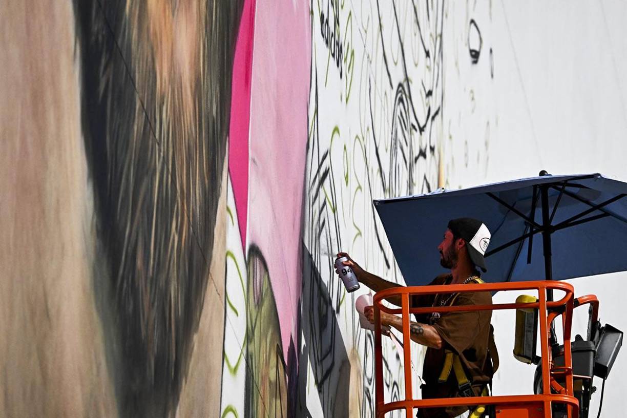Subido a una grúa, el argentino Maximiliano Bagnasco trabaja en un enorme retrato del futbolista en la fachada de un edificio.