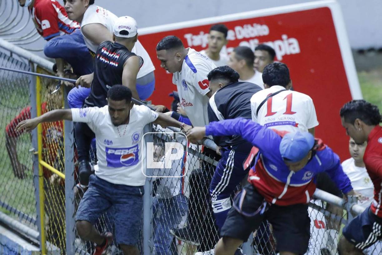 Aficionados olimpistas se saltaron el alambrado del sector preferencial para buscar a los hinchas del Motagua.
