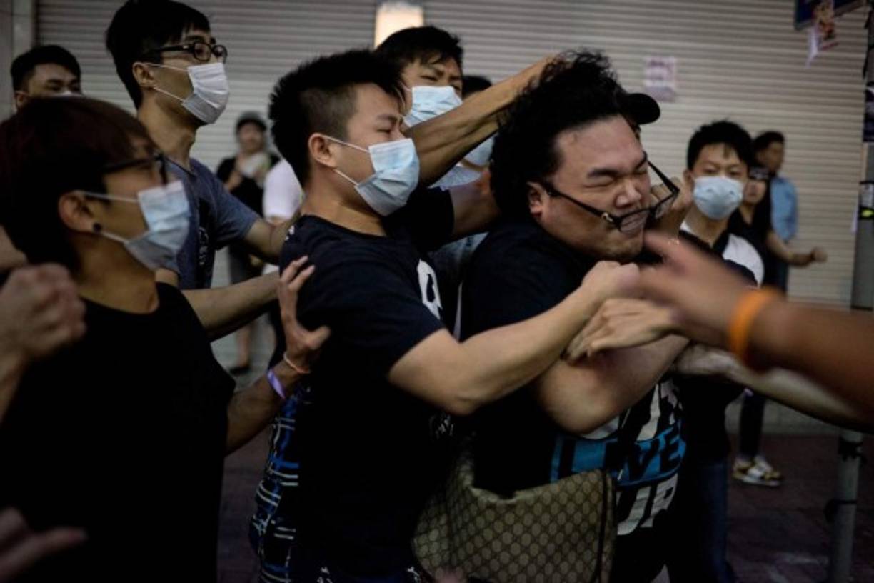 Un grupo de hombres da una paliza a un hombre que intentó impedir que retiraran las barricadas de una zona de protesta a favor de la democracia en el distrito de Causeway Bay de Hong Kong el 3 de octubre de 2014 en Hong Kong. AFP