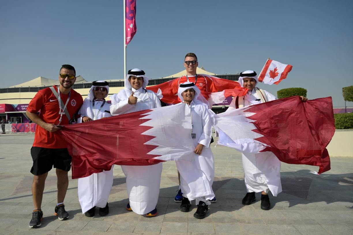 Fans of Canada pose for a picture with fans of Qatar as they arrive at Al-Bayt Stadium in Al Khor, north of Doha, on November 20, 2022, before the kick-off match of the Qatar 2022 World Cup football tournament between Qatar and Ecuador. (Photo by Juan MABROMATA / AFP)
