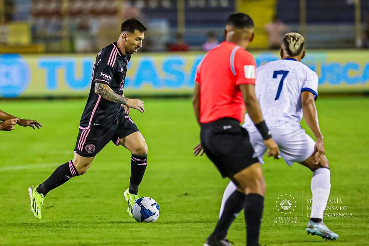 Messi siendo marcado por el capitán salvadoreño Darwin Cerén y ante la mirada del árbitro Iván Barton.