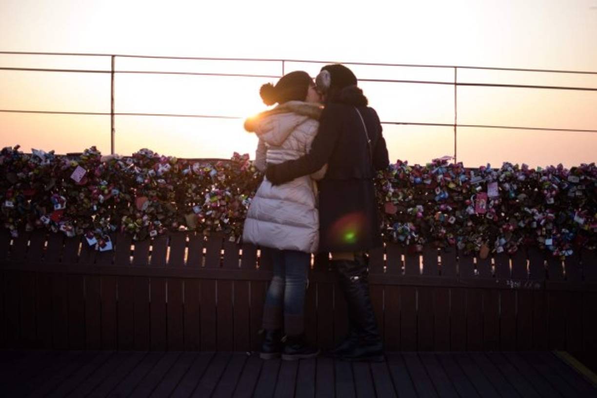 Dos enamorados se besan en Seúl ante un mirador donde las parejas cuelgan candados como señal de compromiso.
