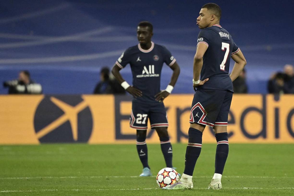 Kylian Mbappé, con los brazos en la cintura, observando la celebración del Real Madrid tras el gol de Benzema.