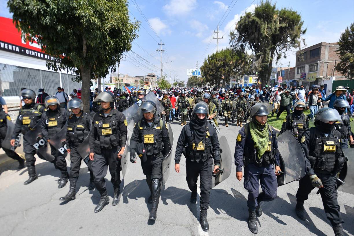 Members of the police escort supporters of former President Pedro Castillo while they march to the center of the city of Arequipa, Peru, demanding the closure of Congress and the release of Castillo, on December 14, 2022. - Former Peruvian President Pedro Castillo, accused of "rebellion" and "conspiracy", will continue to be detained at a police base after an appeals court declared his request for freedom unfounded on Tuesday while protests that have left seven dead and 200 injured continue. (Photo by Diego Ramos / AFP)