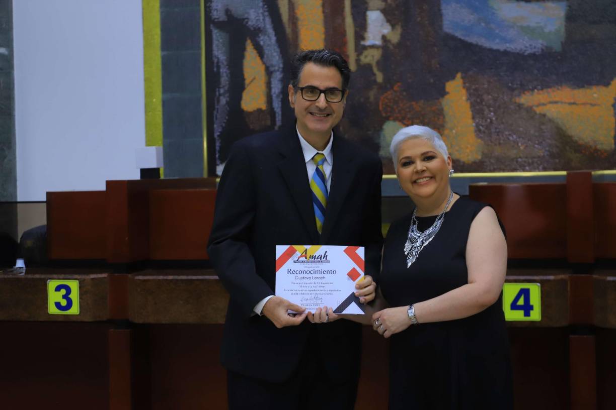 Gustavo Larach recibe en manos de la artista Pamela Letona, un reconocimiento por su proyección como curador de la exposición de obras. 