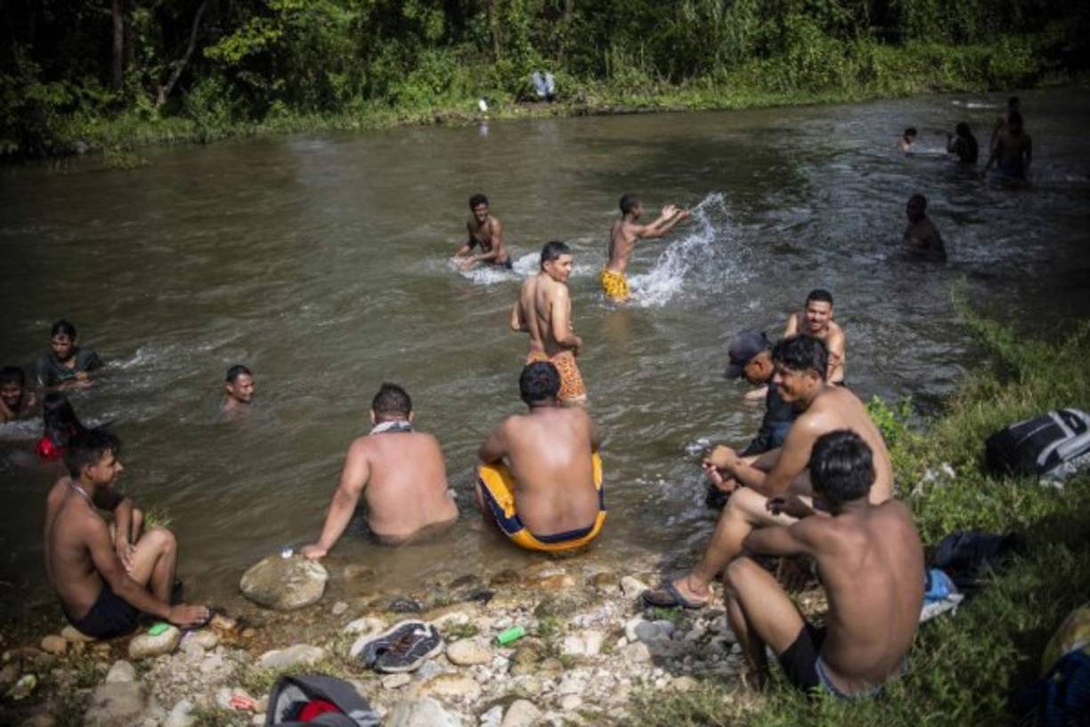 En la imagen, varios migrantes se muestran muy contentos de poder darse un baño.