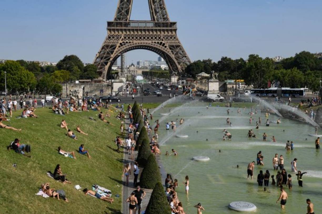 En plena temporada alta, los turistas tomaban por asalto las fuentes, incluyendo la del Trocadero en París, frente a la Torre Eiffel, para refrescarse.