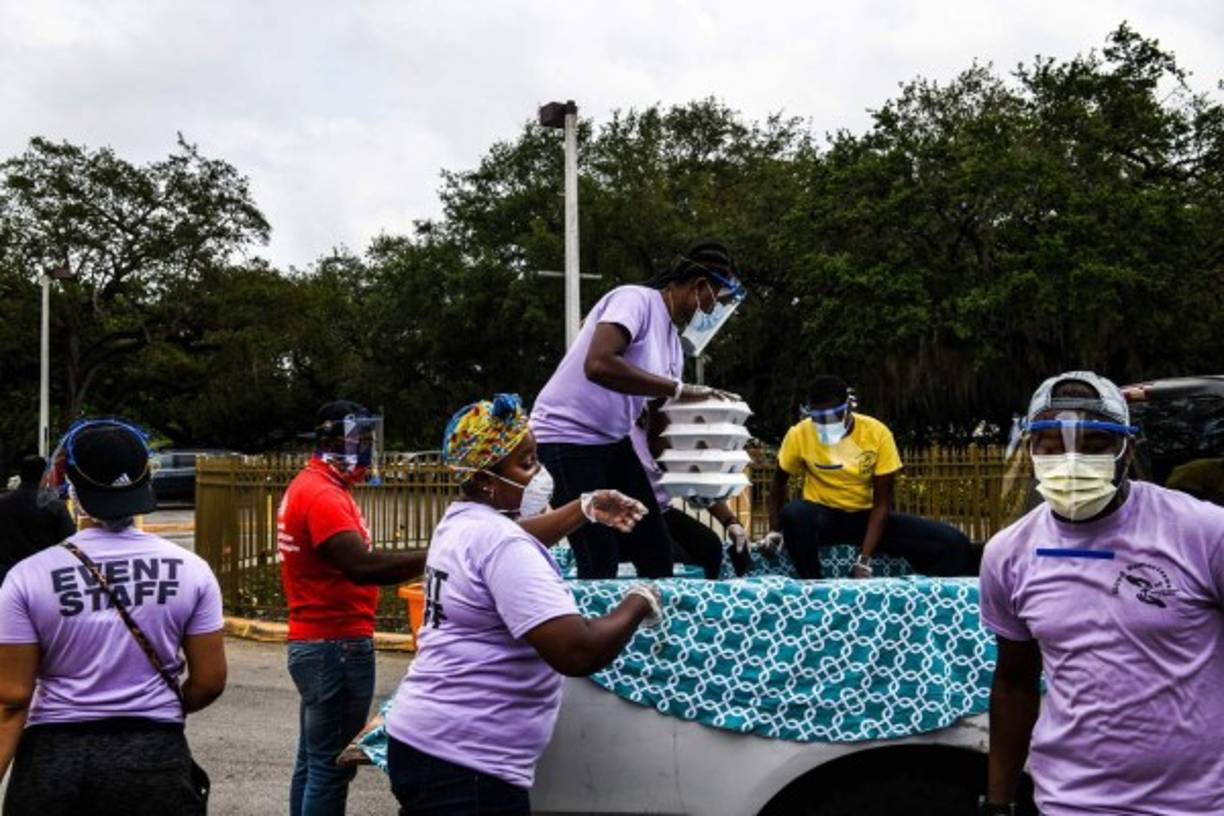 In recognition of Easter, volunteers distribute food to people in need in the Little Haiti community at Notre Dame DHaiti Catholic Church, in Miami, Florida on April 11, 2020. - Drive-thru food distribution sites were set up across South Florida on April 11, 2020 as the financial grip of the coronavirus pandemic hits home. (Photo by CHANDAN KHANNA / AFP)