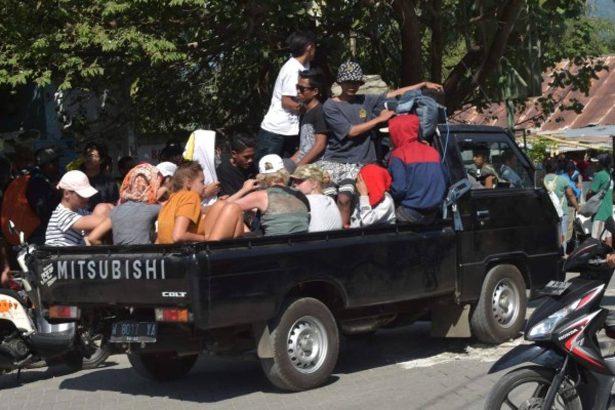Foreign tourist and local residents ride on the back of a vehicle in Bangsal, North Lombok on August 6, 2018, the day after a 6.9 magnitude earthquake struck the area.<br/>More than 1,000 tourists were being evacuated from Indonesia's tiny Gili islands on August 6 after a powerful quake struck neighbouring Lombok, killing 91 people and injuring hundreds. / AFP PHOTO / ADEK BERRY