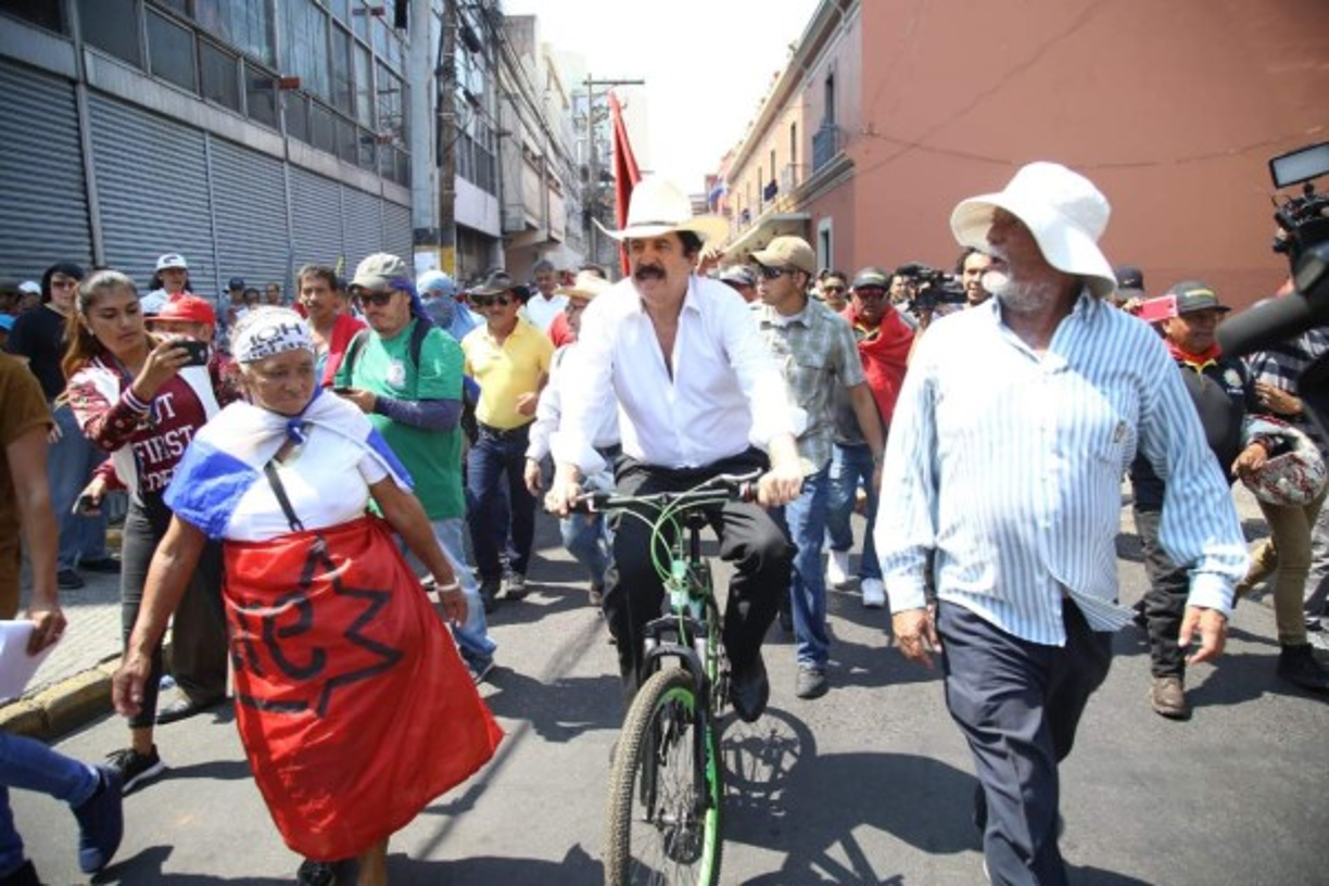 El expresidente Manuel Zelaya Rosales una vez más llegó en su bicicleta para apoyar a los trabajadores. Entre gritos, Mel recorrió las calles del centro de la ciudad en su 'bici'