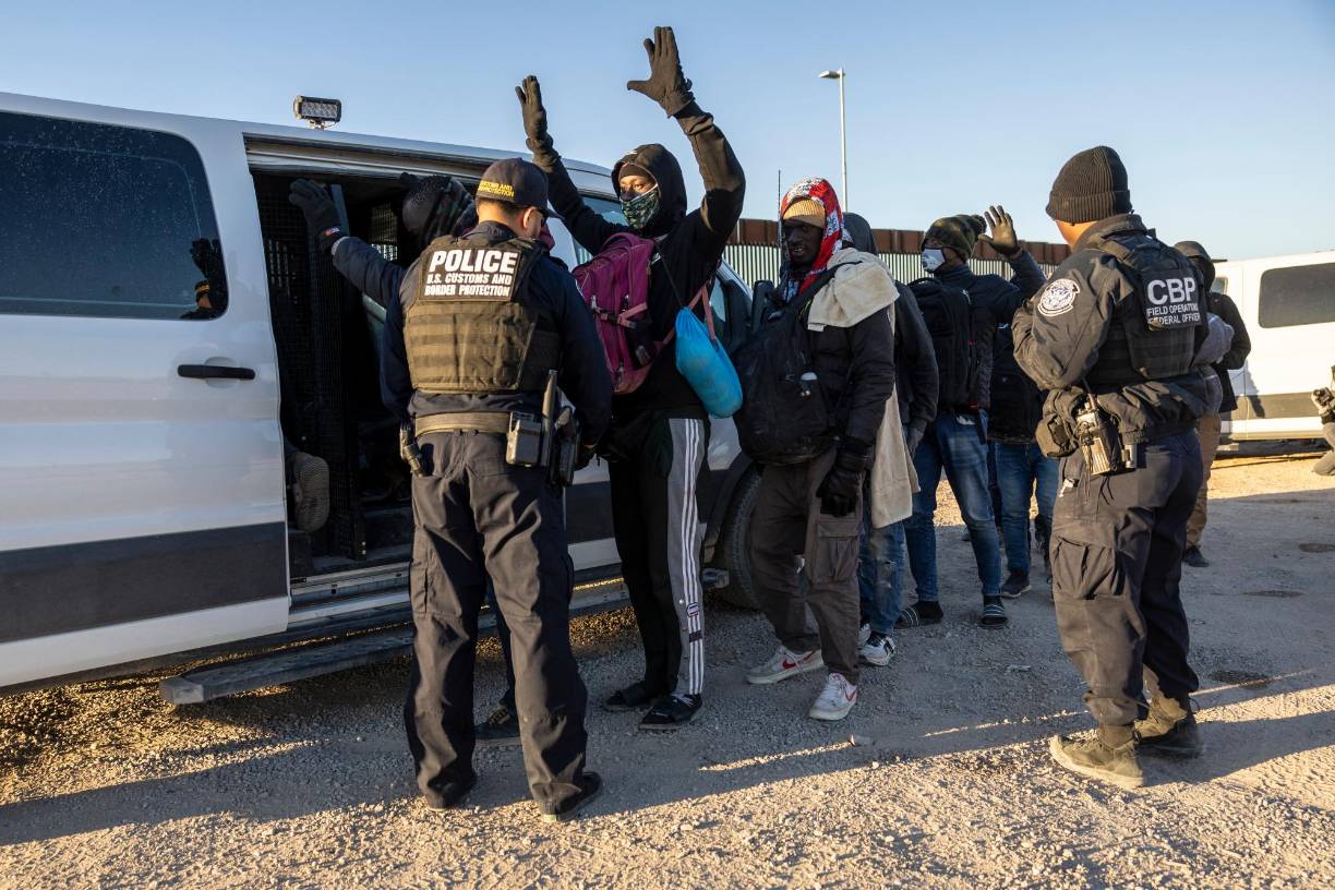 Agentes fronterizos revisan a migrantes antes de procesarlos tras cruzar ilegalmente la frontera sur de EEUU.