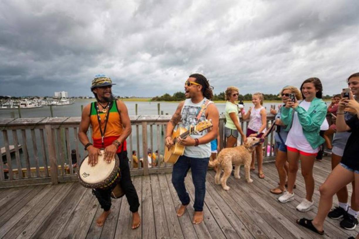 Un grupo de personas acompaña a la banda Paleo Sun durante un toque improvisado en el restaurante Dockside hoy, jueves 13 de septiembre de 2018, en Wilmington, Carolina del Norte (EE.UU.). El huracán de categoría 2 Florence, cuyas bandas de lluvia de los bordes y vientos afectan ya la costa de Carolina del Norte, se debilitó en la últimas horas ligeramente mientras se aproxima a la costa sureste de Estados Unidos. EFE