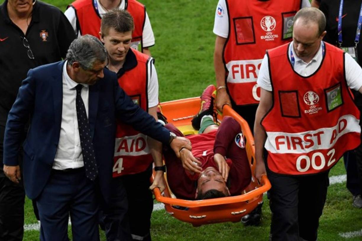 Portugal's forward Cristiano Ronaldo is comforted by Portugal's coach Fernando Santos as he is carried on a stretcher off the pitch by medics after an injury following a clash with France's forward Dimitri Payet (not pictured) during the Euro 2016 final football match between Portugal and France at the Stade de France in Saint-Denis, north of Paris, on July 10, 2016. / AFP PHOTO / MIGUEL MEDINA