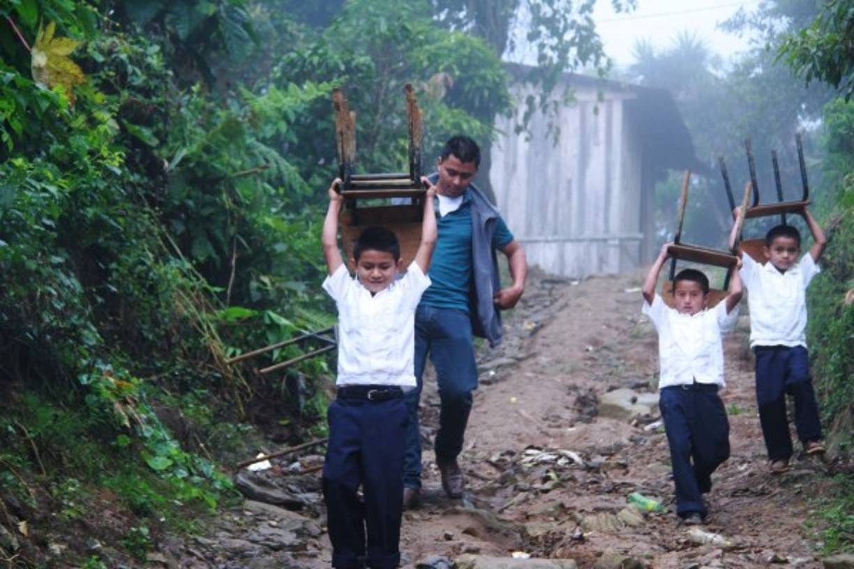 Los niños cargan con los pupitres en zonas inclinadas.
